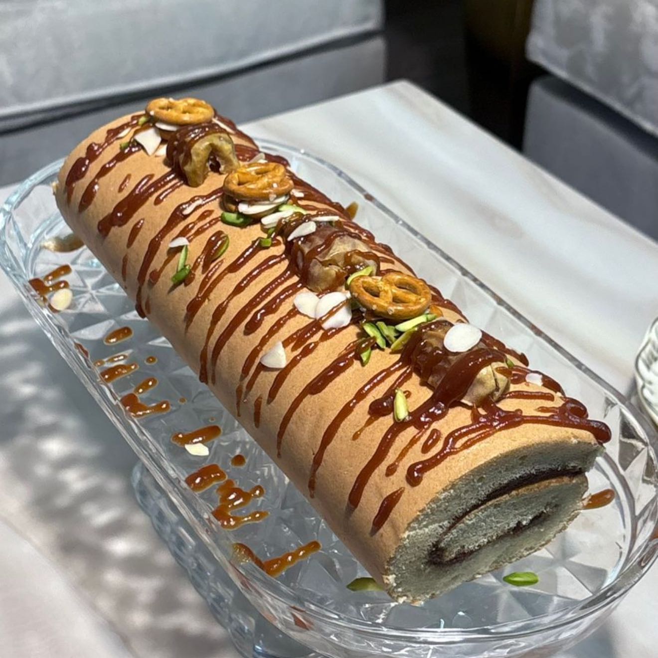 كيك رول بنكهة التمر الفاخر، طري ولذيذ بطعم متوازن يجمع بين حلا التمر ونكهة الكراميل، مزين بالمكسرات لمذاق راقٍ ومميز🌴